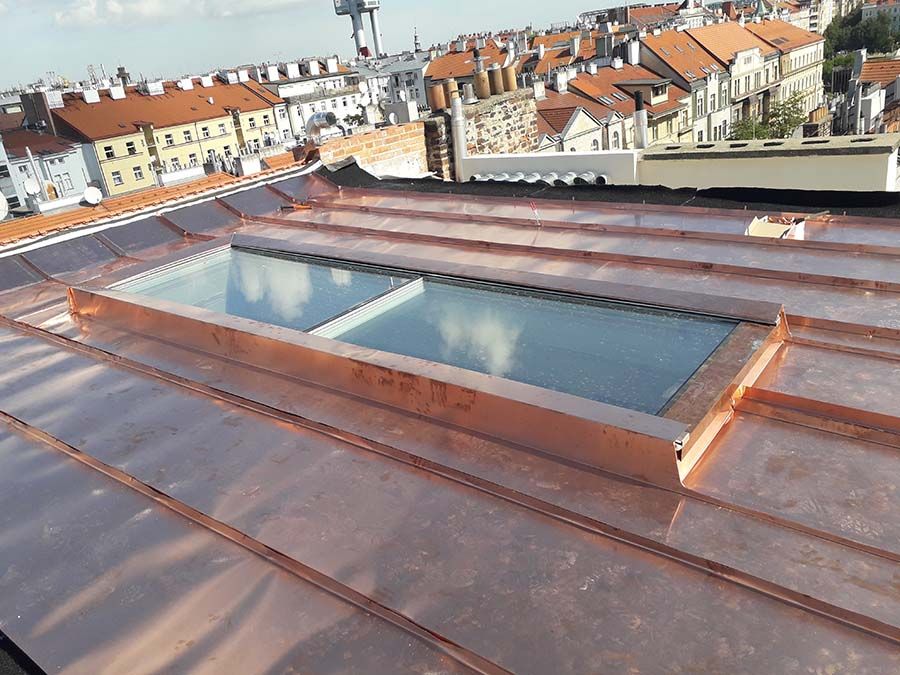 Plochý prosklený světlík v měděné střeše nad zástavbou